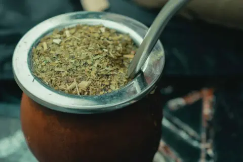 Ein traditioneller Mate-Tee-Becher aus Leder, gefüllt mit getrockneten Mate-Blättern und einer Metall-Bombilla.
