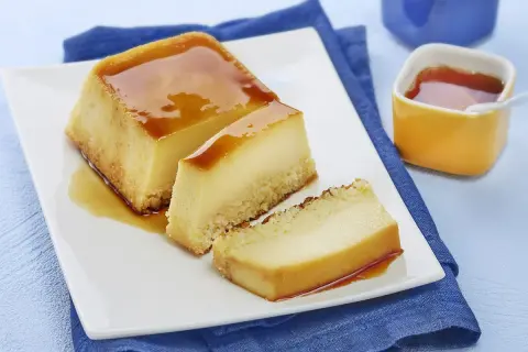 Un délicieux flan au lait concentré, parfait pour une recette flan lait concentré Nestlé. Servi sur une assiette blanche avec un coulis de caramel.