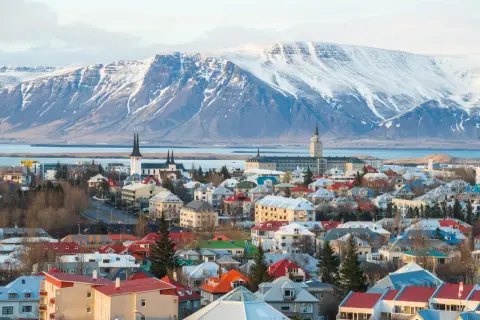 Kolorowe dachy Reykjaviku pod ośnieżonymi górami. Widok na miasto, kościoły i budynki, przypominający o jego położeniu na Islandii, gdzie lotniska są kluczowe dla podróży.