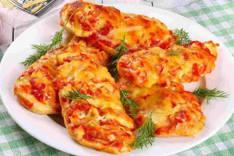 Delizioso petto di pollo alla pizzaiola, cotto al forno con pomodoro e formaggio filante, guarnito con aneto fresco.