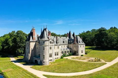 Magnifique chateau dans le Cher, avec ses tours et son parc verdoyant sous un ciel bleu.