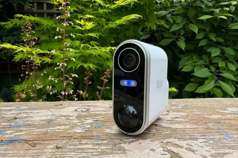 Une caméra de surveillance blanche avec une lumière bleue allumée, posée sur un banc en bois. Un moyen simple pour savoir si une caméra fonctionne.