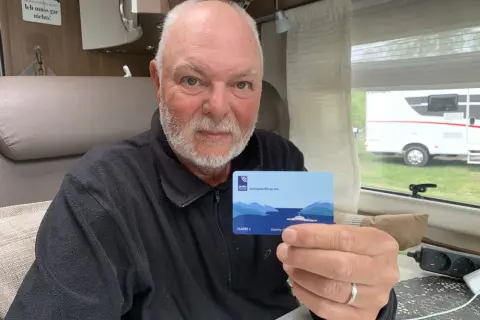 Man håller upp ett AutoPASS-kort för färjor, redo för bila i Norge.