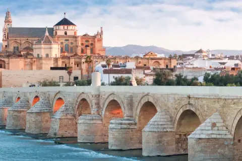 El Puente Romano cruza el Guadalquivir hacia la impresionante mezquita catedral de Córdoba, bañada por la luz del amanecer.