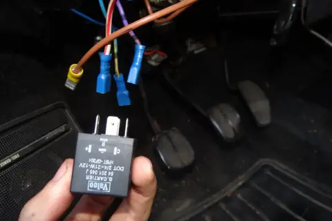 Main tenue, un relais Valeo pour clignotant fonctionne par intermittence. Des fils électriques sont connectés sous le tableau de bord.