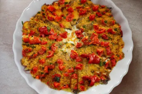 Alici al forno dorate e succulente, ricoperte di pomodorini freschi e pangrattato croccante. Un piatto semplice e gustoso.