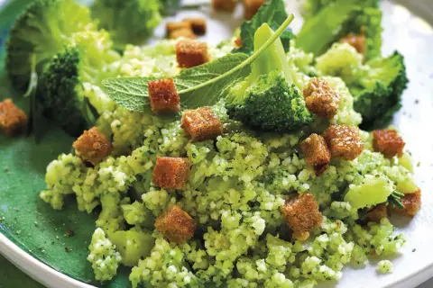 Un gustoso cous cous con broccoli, crostini dorati e foglie di menta fresca, un piatto colorato e salutare.