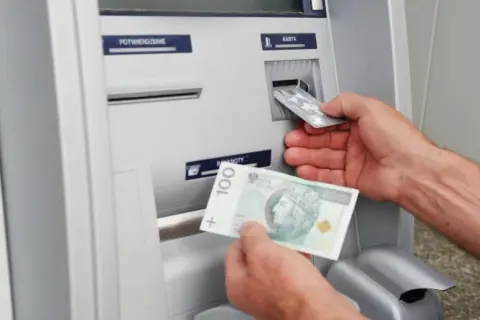 Wpłatomat przyjmuje banknoty, w tym 100 zł. Widać też wkładanie karty.