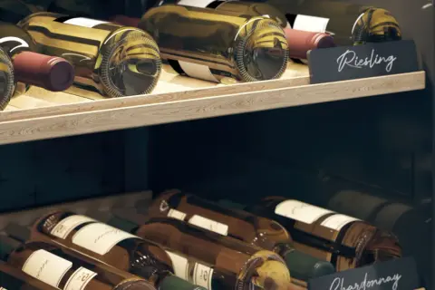 Drewniane półki piwniczki na wino z butelkami Riesling i Chardonnay. Idealne miejsce, jak przechowywać wino w butelkach.