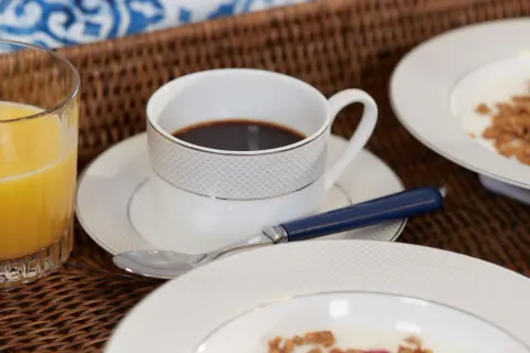 Frukostbricka med kaffe, juice och flingor. En kopp kaffe med en sked, perfekt för att njuta av morgonen. Undrar hur många koppar kaffe per paket?