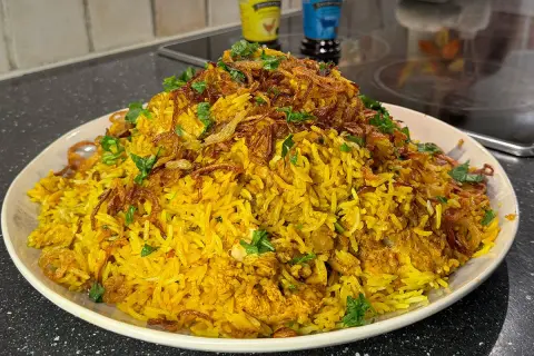 En stor portion gyllene biryani med kyckling, toppad med krispig lök och färsk koriander. Ett perfekt biryani recept för en festmåltid.