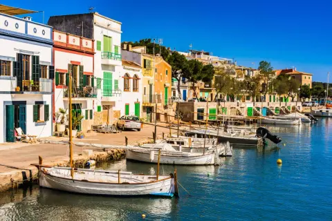 Bunte Häuserfront am Hafen, Boote im Wasser – ein idyllischer Urlaub auf Mallorca.