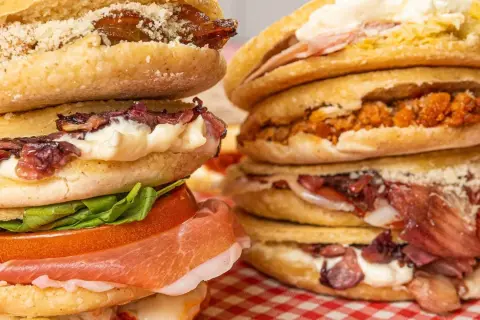 Ecco cosa sono le tigelle: dischi di pane morbido farciti con salumi, formaggio, verdure e salse, un vero piacere per il palato.