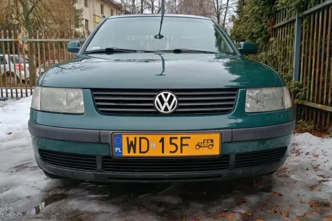 Zielony samochód zabytkowy, może 25 czy 30 lat, z charakterystycznym znaczkiem VW na grillu, stoi na oblodzonym podjeździe.