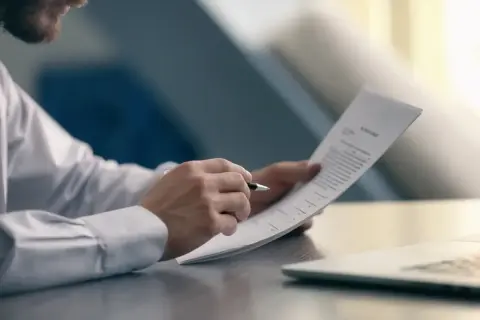 Mężczyzna w białej koszuli analizuje dokument, sprawdzając warunki, kiedy pracodawca nie musi wypłacić odprawy.