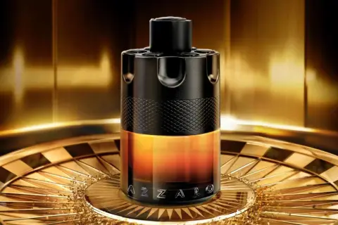 Elegancki flakon perfum Azzaro Wanted w odcieniach czerni i złota, stojący na ozdobnej tacy.