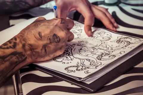 Ein Tätowierer entwirft eine Tintenfisch-Vorlage. Die Frage, wie lange dauert ein kleines Tattoo, hängt von der Komplexität ab.