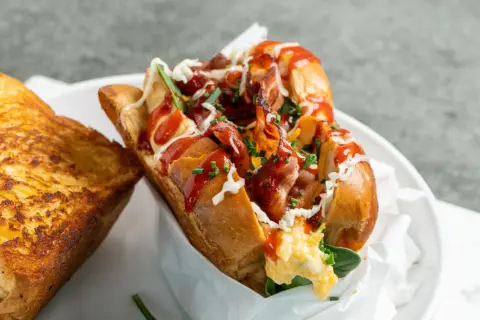 Herzhaftes Eggdrop Sandwich mit knusprigem Speck, Rührei, Käse und Ketchup, serviert mit geröstetem Käse-Toast.
