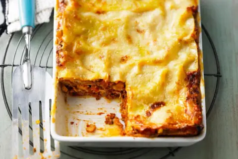 Herzhaftes Lasagne Rezept mit goldbrauner Käsekruste, bereit zum Servieren. Ein Stück wurde bereits entnommen.