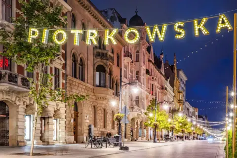 Ulica Piotrkowska nocą, iluminowana neonami i girlandami świateł. Idealne miejsce, by poczuć klimat Łodzi i zastanowić się, co zwiedzić w Łodzi.