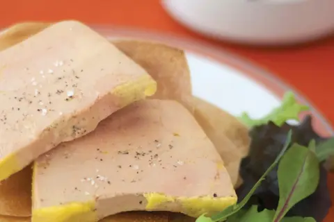 Tranches de foie gras poêlé, assaisonnées de sel et poivre, sur une galette. Le temps de cuisson foie gras bain-marie est crucial pour cette texture.