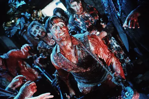 Krwawy mężczyzna otoczony przez zombie. Scena pełna grozy, idealna dla fanów **horrory 18+**.