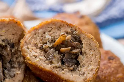 Kotlety mielone z pieczarkami, przekrojone na pół, ukazujące soczyste nadzienie.