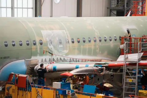 Arbeiter im Airbus-Werk montieren Flugzeugteile. Der Airbus-Tarifvertrag regelt die Arbeitsbedingungen.