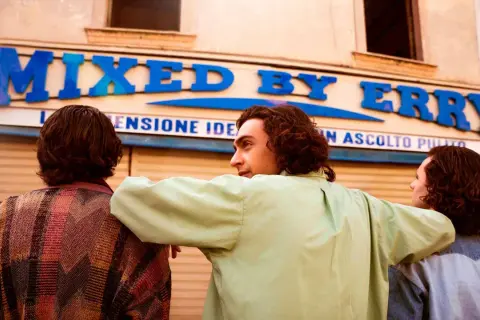 Tre amici guardano un negozio con insegna "MIXED BY ERRY".