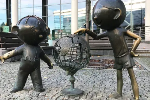 Dwie postacie z brązu odkrywają świat na globusie. Jedna z nich wskazuje palcem na kontynent. To jedna z bielsko-biała atrakcji.