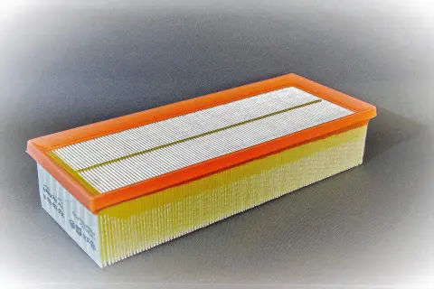 Filtro de aire rectangular con marco naranja y pliegues amarillos. Pregúntate cada cuanto se cambia el filtro de aire para mantener tu motor en óptimas condiciones.