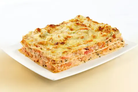 Une part généreuse de lasagne au saumon, avec ses couches de pâtes, de poisson rose et de fromage gratiné, prête à être dégustée.