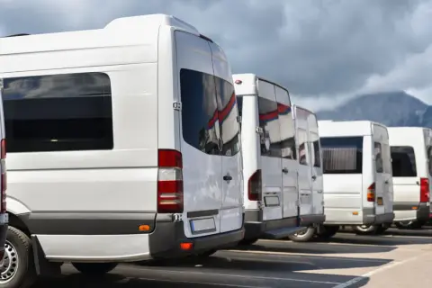 Białe busy czekają na pasażerów. Planujesz wycieczkę do Doliny Chochołowskiej? Zobacz, dolina chochołowska jak dojechać z Zakopanego.