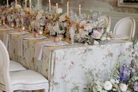 Magnifique table dressée pour un mariage de froment, avec des fleurs pastel, des bougies et une nappe à motifs floraux.