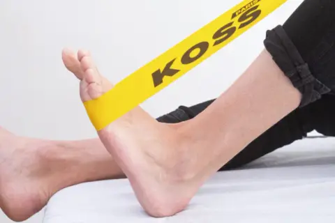 Exercice avec élastique jaune pour soulager la périostite tibiale.