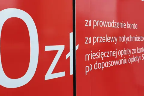 Na czerwonym tle biały napis "0zł" i lista opłat za konto, przelewy i kartę w Santander.