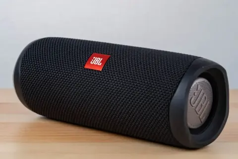 Czarny głośnik JBL na drewnianym blacie. Dowiedz się, jak podłączyć głośnik JBL do komputera przez USB, aby cieszyć się lepszym dźwiękiem.