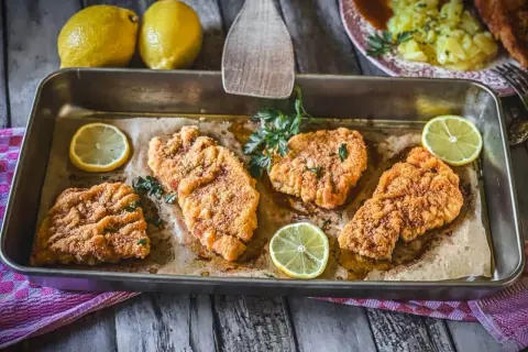 Vier saftige putenschnitzel im Ofen gebacken, garniert mit frischer Petersilie und Zitronenspalten.