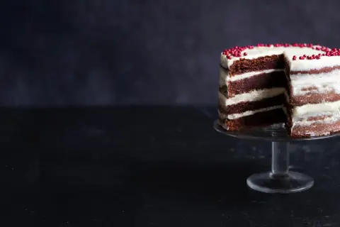 En läcker red velvet cake med lager av choklad och krämig frosting, dekorerad med röda pärlor.