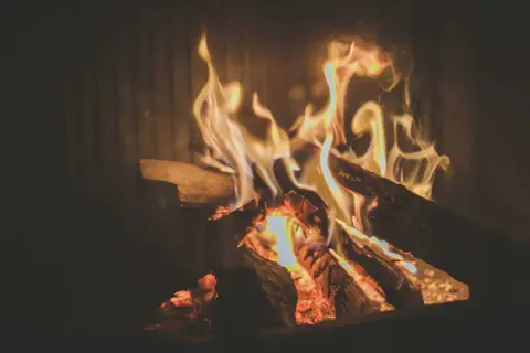 Glühendes Kaminfeuer mit Holzscheiten. Die brennholz trocknen dauer tabelle ist hier nicht sichtbar, aber das Feuer wärmt.