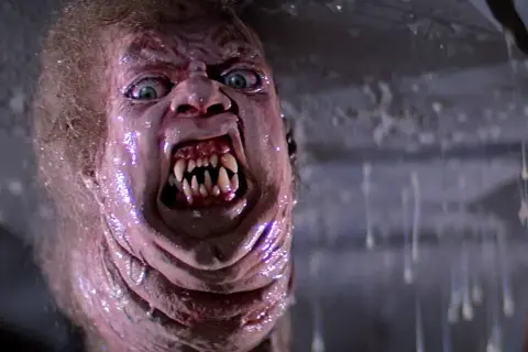 Potwór z klasycznych **filmy sci-fi lata 80.** z przerażającymi zębami i zielonymi oczami, w mokrym, obrzydliwym otoczeniu.