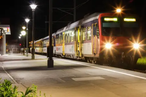 Ein Zug mit roten und blauen Waggons steht nachts am Bahnsteig. Die Scheinwerfer leuchten hell. Ein perfekter Start für eine Reise mit Interrail Italien.