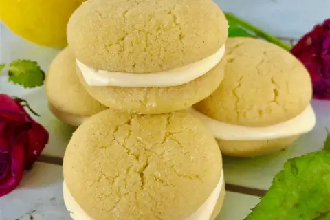 Små, runda kakor med krämig fyllning, perfekt för ett enkelt lemoncurd recept. En gul citron syns i bakgrunden.