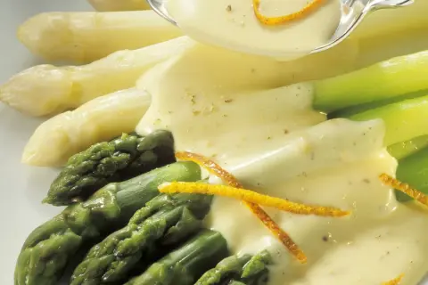 Frischer Spargel, weiß und grün, wird mit einer cremigen Sauce und Orangenzesten serviert. Perfekt zum Spargel kochen.