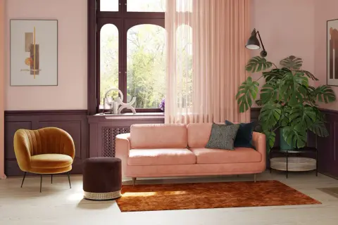 Ein pfirsichfarbenes Sofa mit modernen Kissen, umgeben von warmen Tönen, zeigt, welche Sofa Farbe ist modern. Ein gelber Sessel und ein brauner Hocker ergänzen den Look.