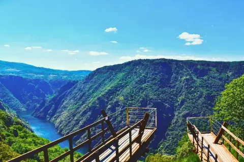 Mirador de madera con vistas a un cañón verde y un río azul. Imprescindible que ver en Ribeira para disfrutar de la naturaleza.