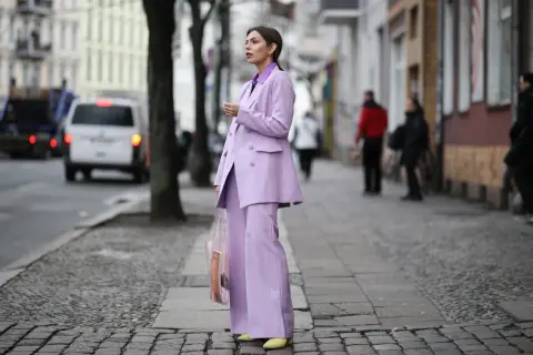 Elegancki garnitur w kolorze liliowym z czym łączyć? Modelka prezentuje stylizację z żółtymi czółenkami i transparentną torbą.