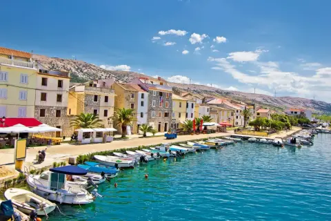 En kuststad i Kroatien med färgglada hus, en hamn full av båtar och en bergig bakgrund. Här finns fakta om Kroatien.