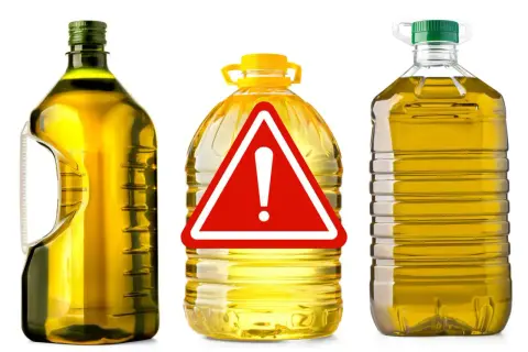 Bottiglie di olio di oliva con un cartello di pericolo. Attenzione all'olio di oliva lampante, potrebbe non essere quello che pensi.