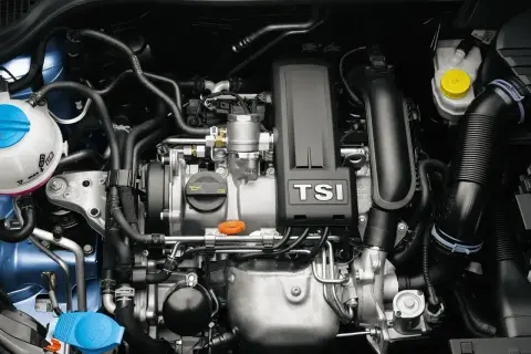 Silnik 1.2 TSI EA211 z turbosprężarką. Widoczne elementy układu chłodzenia, dolot powietrza i osłona silnika z napisem TSI.
